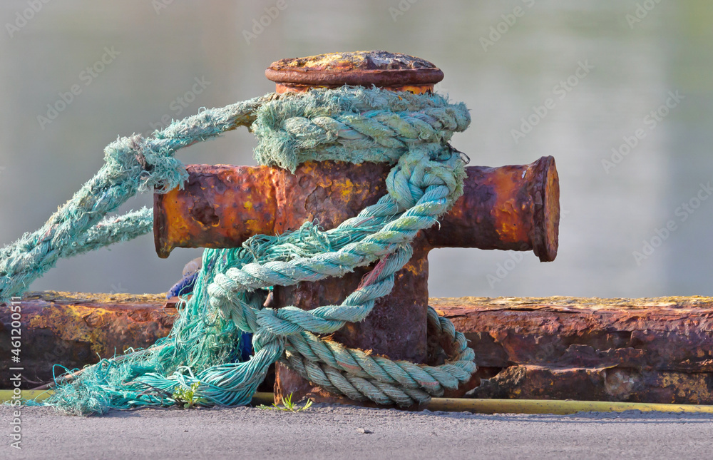 Mooring nautical bollard with green rope around it