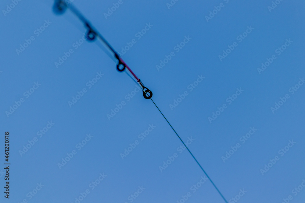 Stretched fishing line close-up. Fishing rod against the sky. Seasonal fishing. High quality photo Stretched fishing line close-up. Fishing rod against the sky. Seasonal fishing. High quality photo