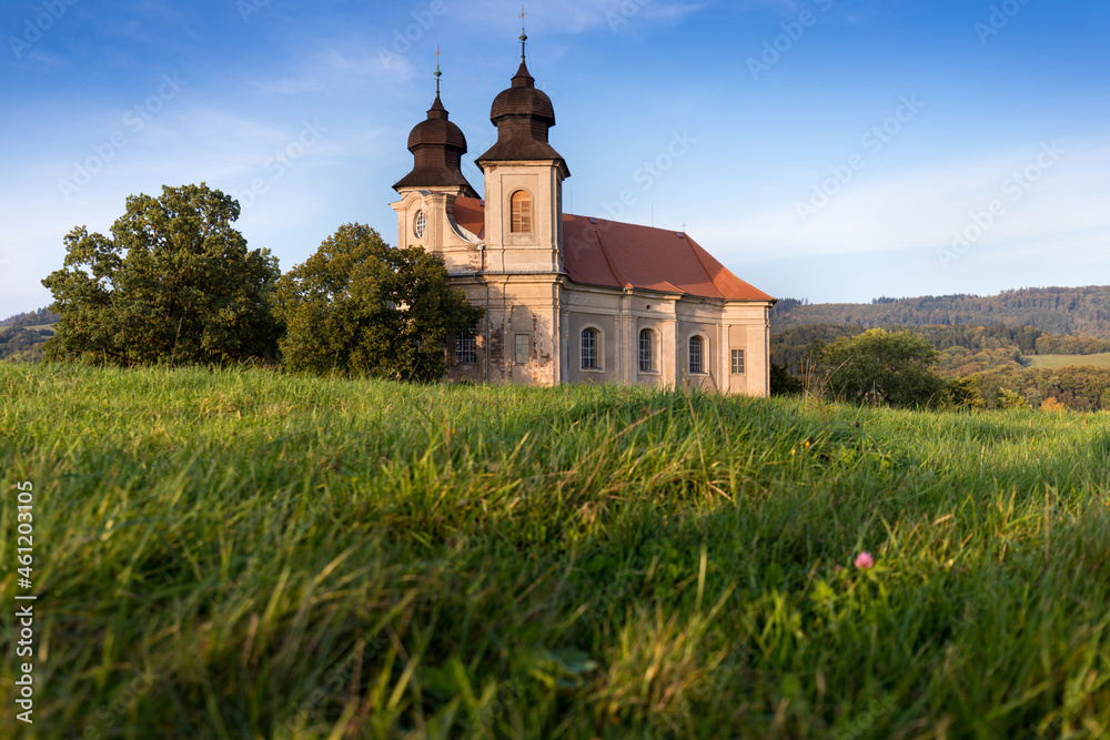 Church of St. Margaret from the 18th century near Šonov. Beautiful church chapel in middle of fields in czech countryside broumovsko region with hills of broumov walls on background. Czech landscape.