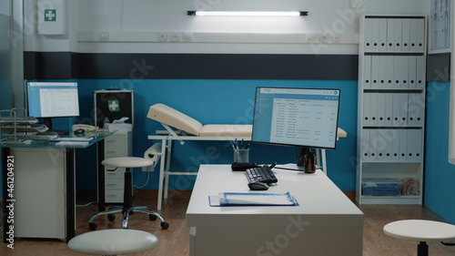 Empty doctors office with medical equipment and computer on desk at healthcare facility. Nobody in cabinet with documents and instruments for checkup and consultation. Space for examination © DC Studio