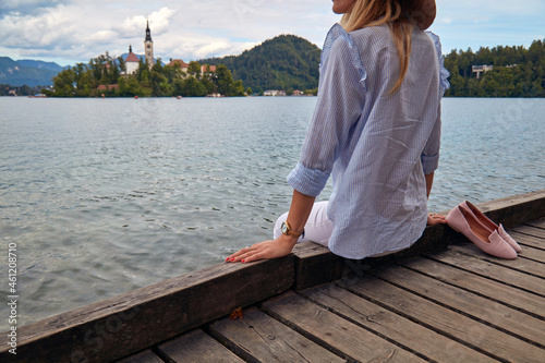 Young adult tourist woman enjoying barefoot on a lake wooden pier. © astrosystem