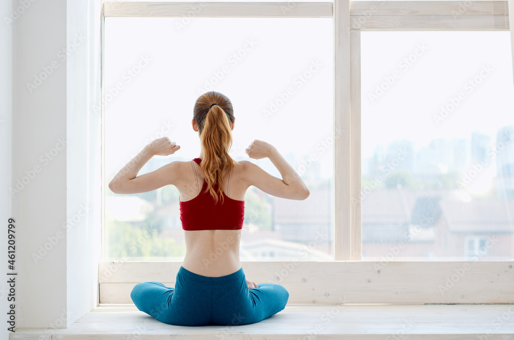sportive woman doing yoga exercise asana near the window