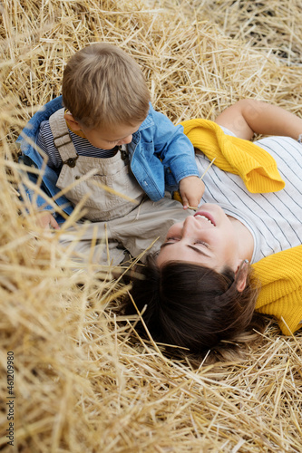 Beautiful  young mother and cute  son toddler are having fun on a haystack in the field 