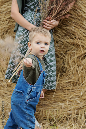 Beautiful  young mother and cute  son toddler are having fun on a haystack in the field 