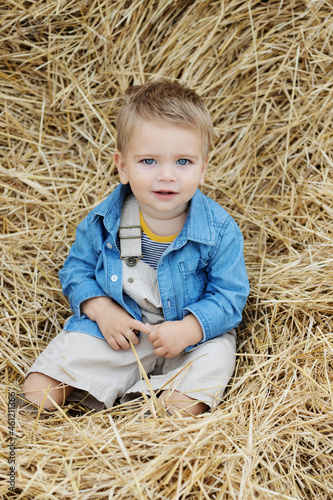Beautiful  young mother and cute  son toddler are having fun on a haystack in the field 