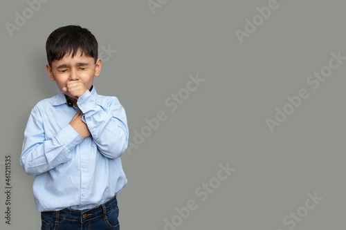 Cute little boy is coughing, on gray background