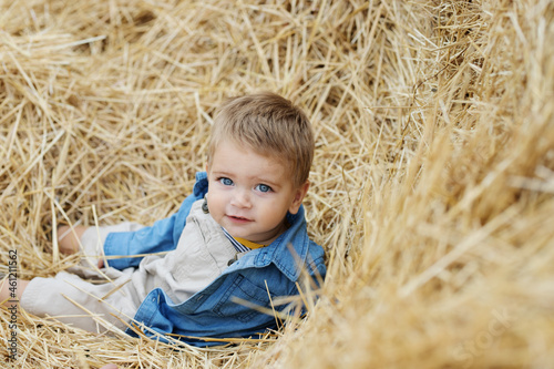 Beautiful  young mother and cute  son toddler are having fun on a haystack in the field 