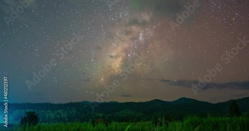 Motion Time lapse of The Milky Way  in night sky over the paddy field with a photographer set up a camera to photograph astronomy at Mae Hong Son Northern Thailand.