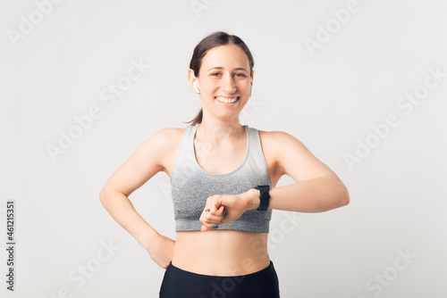 Young smiling girl is wearing sportswear, smart watch and ear buds.