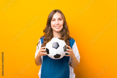 Handsome young woman is holding a soccer ball over yellow background. © Vulp