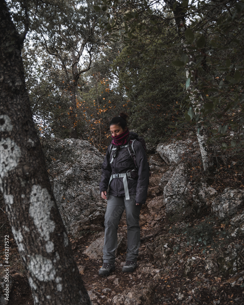 Young woman hiking in the woods with a purple jacket 
