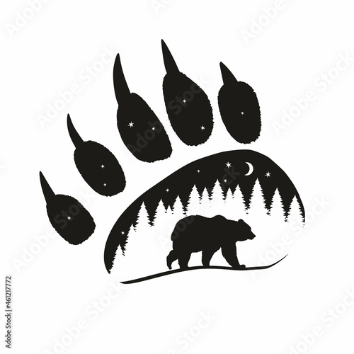 The silhouette of a bear against the background of the forest at night in the imprint of a bear's paw