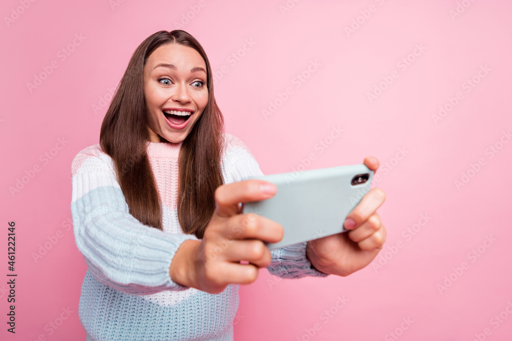 Photo portrait of happy girl playing game on mobile phone excited smiling isolated on pastel pink color background Photo portrait of happy girl playing game on mobile phone excited smiling isolated on pastel pink color background