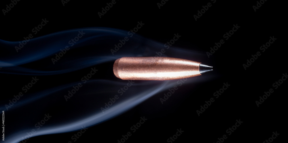 Flying copper bullet with smoke behind on black