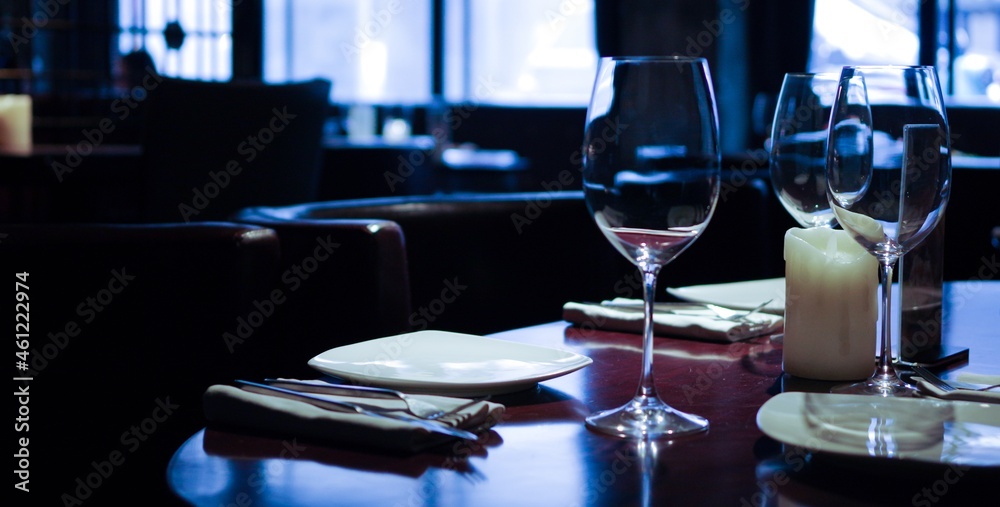 table setting in empty restaurant with clean wineglasses and white candle on wooden table table setting in empty restaurant with clean wineglasses and white candle on wooden table