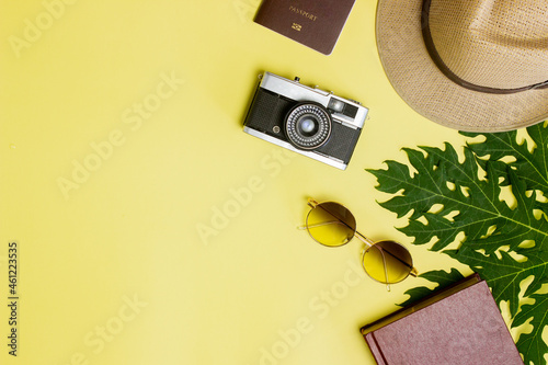 Travel concept with passport, hat, sun glasses, books and camera on yellow background.  photo