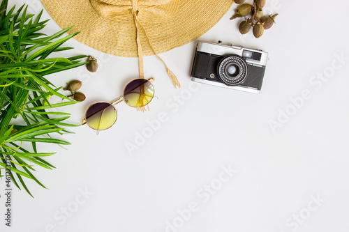 Travel concept with hat, leaves. sun glasses and camera over the whtie table.  photo