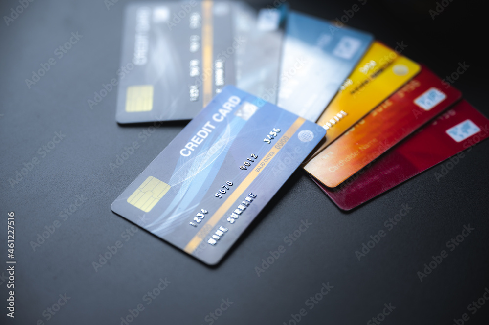 Closeup of group of credit and debit bank cards with NFC machine on a blue table used for online and plastic money transfer while shopping or paying bills Closeup of group of credit and debit bank cards with NFC machine on a blue table used for online and plastic money transfer while shopping or paying bills