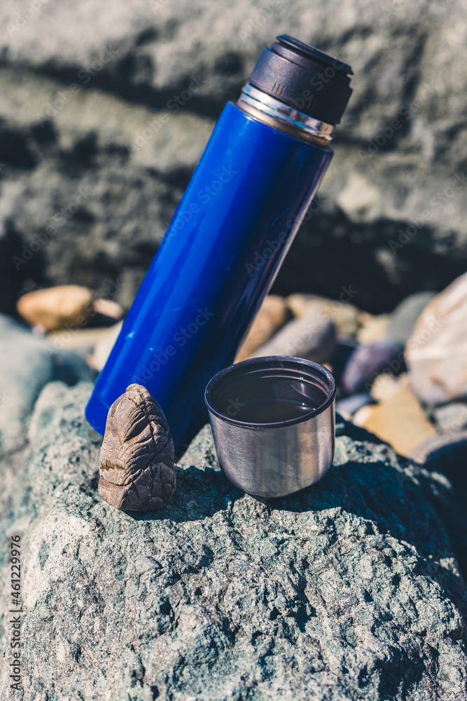 hiking thermos and a cup on the stones hiking thermos and a cup on the stones