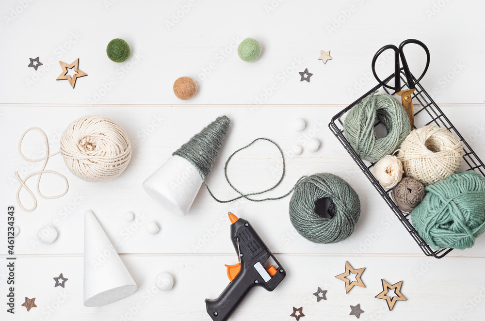 Christmas craft hobby background with handmade yarn cone xmas trees in natural colors. Recomforting, destressing hobby to make christmas decoration. Top view of diy workshop Christmas craft hobby background with handmade yarn cone xmas trees in natural colors. Recomforting, destressing hobby to make christmas decoration. Top view of diy workshop