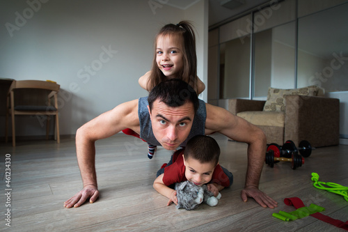 Father doing workout and funny children having fun and playing with him