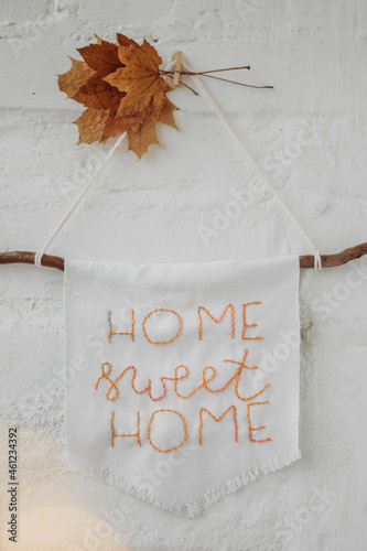White wall with embroidered picture and autumn leaves. Home sweet home.
