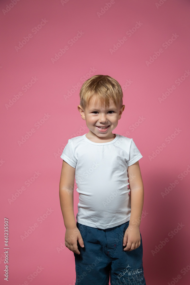 Caucasian boy 3 years old makes faces while looking at camera on pink background Caucasian boy 3 years old makes faces while looking at camera on pink background