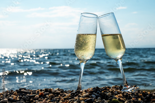 Two glasses of champagne by the sea on the beach. Holiday celebration. Vacation concept.