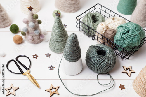 Christmas craft hobby background with handmade yarn cone xmas trees in natural colors. Recomforting, destressing hobby to make christmas decoration. Top view of diy workshop photo