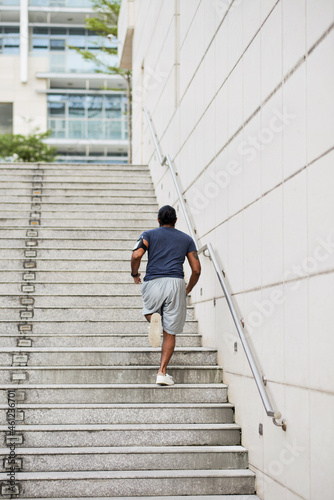 Wallpaper Mural Rear view of sporty man with phone arm band running up stairs while practicing stair workout in city Torontodigital.ca