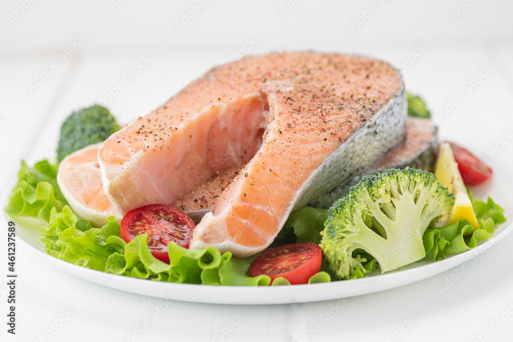 Raw uncooked salmon steak with fresh vegetables.