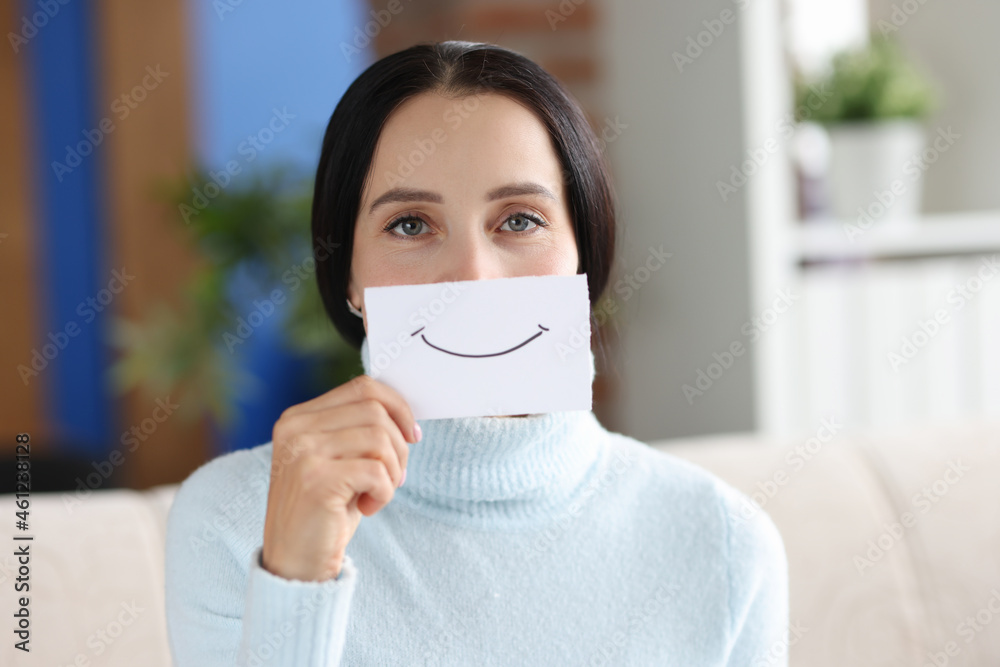Portrait of young woman holding paper with painted smile closup Portrait of young woman holding paper with painted smile closup