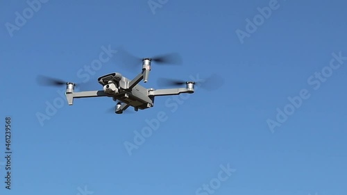 Gray drone flies in the blue clear sky on a summer day, bottom-side view, close-up.