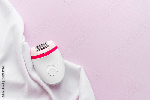 White epilator on soft silk. Hair removal and depilatory concept photo