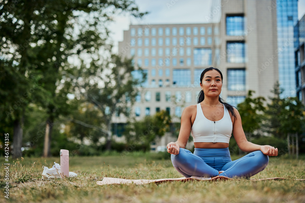 Athletic asian woman with hair bun in tight sportswear practicing yoga.