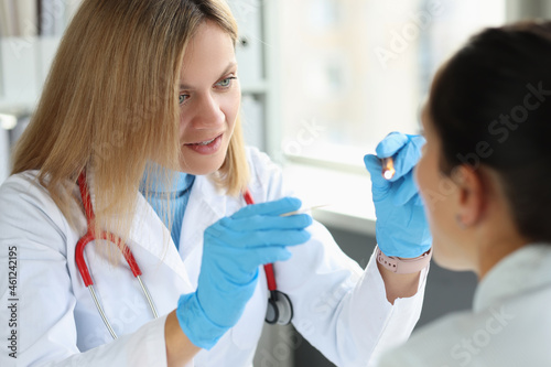 Female ENT doctor examines patient throat closeup