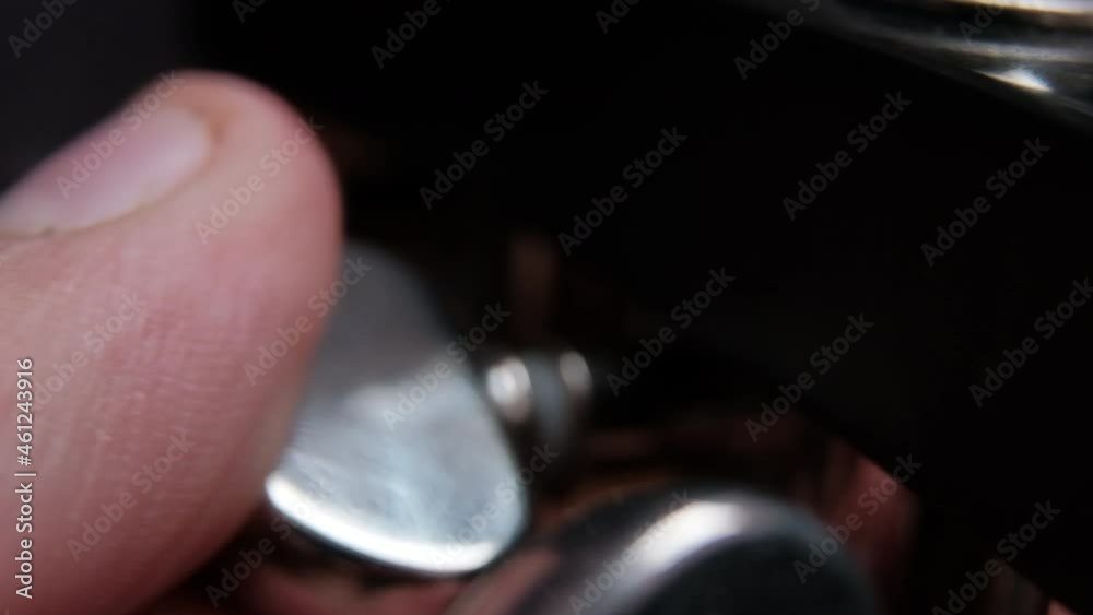 Fingers touching the turning keys of classic electric guitar Fingers touching the turning keys of classic electric guitar
