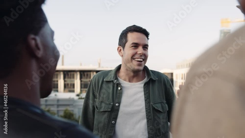 Adult Caucasian Male and Caucasian female socialising with a diverse group of friends at rooftop party. Chatting lightheartedly at sunset. High quality image. photo