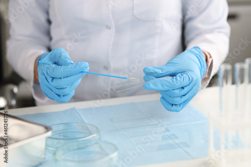 Doctor in gloves holds brush for smears and glass in laboratory photo