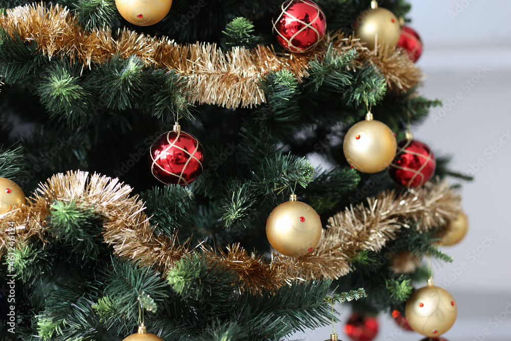 Artificial Christmas tree decorated with red-gold balls and tinsel Artificial Christmas tree decorated with red-gold balls and tinsel