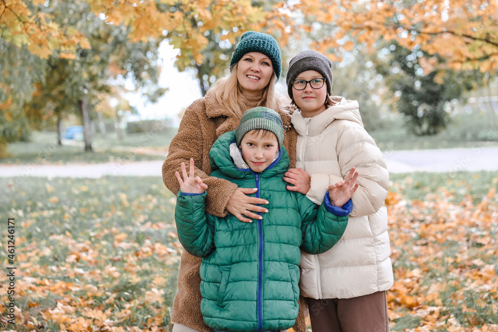 Happy family walking in sunny park and throws orange maple leaves. mother with kids enjoying autumn weather outdoors Happy family walking in sunny park and throws orange maple leaves. mother with kids enjoying autumn weather outdoors