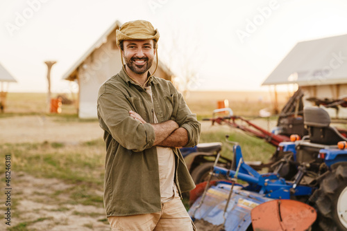 White bristle man in hat working with tractor on farm