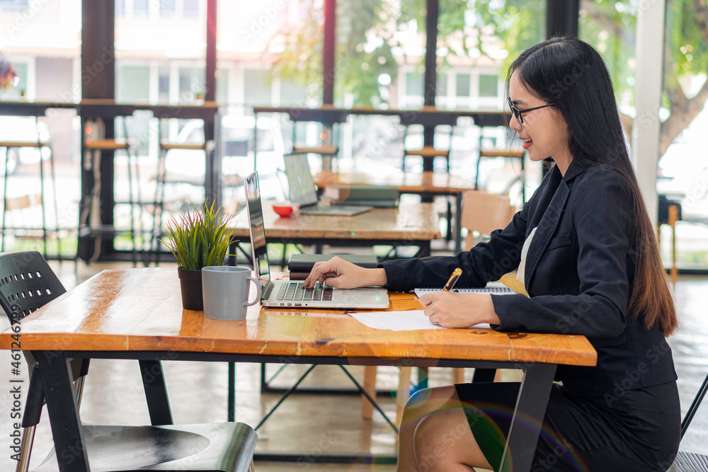 Businesswoman working in a coffee shop with laptop and calculator and notebook. Concept of working in accounting, finance, and investment. Businesswoman working in a coffee shop with laptop and calculator and notebook. Concept of working in accounting, finance, and investment.