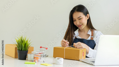 Asian girl startup Small sme business owners work with laptop computers and smartphones at work. with parcel paper boxes for delivery to customers online selling, eCommerce, packing ideas, work from h