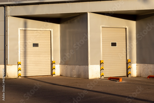Industrial gray unit facade of storehouse with closed white metal gates doors at sunset