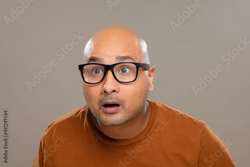 Quadro em tela Portrait of a bald man wearing eyeglasses gaping with amazed expression against plain background