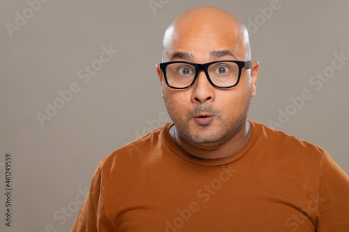 фотографія Portrait of a bald man wearing eyeglasses with amazed expression against plain background