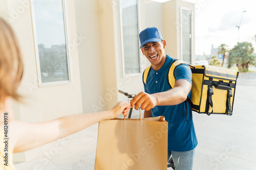 Young Latino delivery boy happily delivering food to the customer.