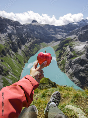 Woman holding a red apple for breakfast after a long hiking in the mountains photo