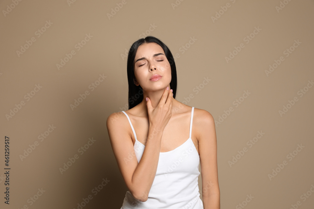 Young woman doing thyroid self examination on beige background Young woman doing thyroid self examination on beige background